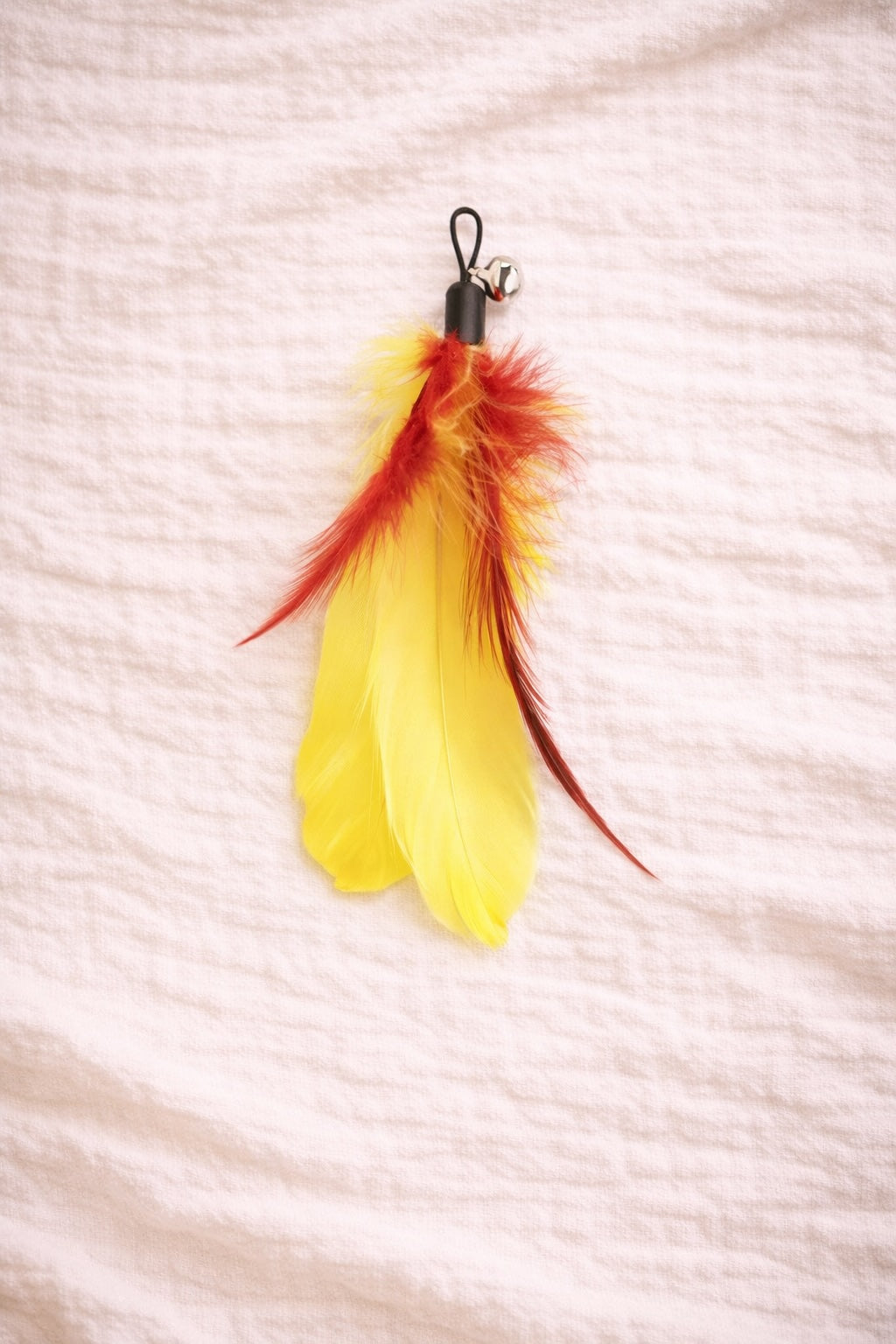 Yellow feather cat toy with red detail and clip connector